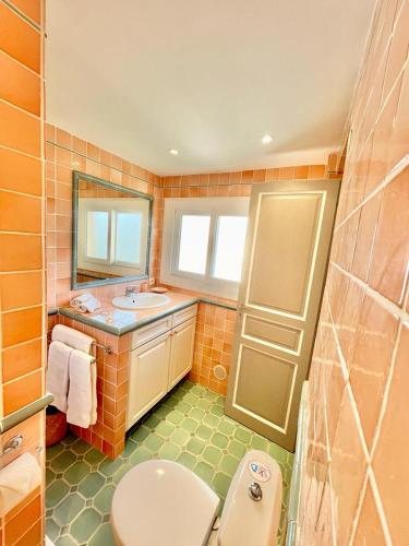 La salle de bains orange est pourvue de toilettes et d'un lavabo. dans l'établissement Chez Camille, à Saint-Tropez