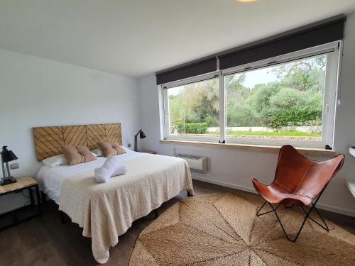 1 dormitorio con cama, ventana y silla en CAN FLOWERS VILLA, en Cala Llonga