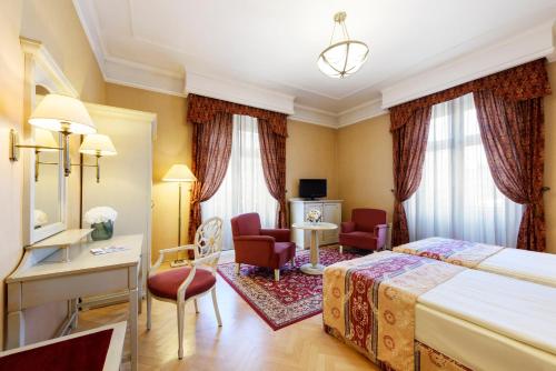 um quarto de hotel com uma cama, uma secretária e cadeiras em Danubius Hotel Astoria City Center em Budapeste
