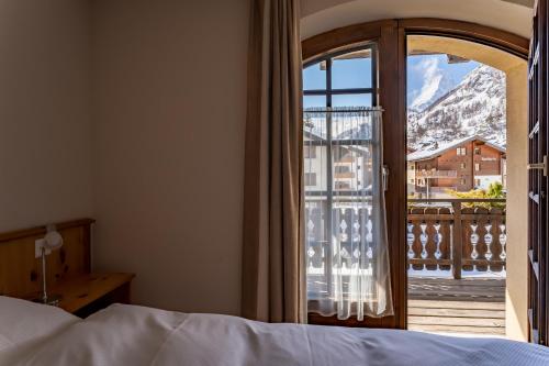 a bedroom with a bed and a view of a balcony at Haus Zer Weidu in Zermatt