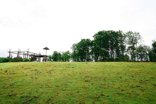 a grassy field with a playground in the background at One khaokho homestay in Khao Kho