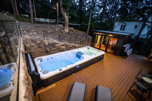 a hot tub on a deck with a grill at 4 Évszak Erdeihotel**** - Mátrafüred in Mátrafüred