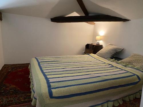 a bedroom with a bed with a striped blanket at Petit paradis in Vic-Fezensac