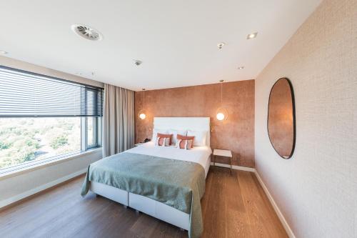 a bedroom with a bed and a large window at Van der Valk Hotel Düsseldorf in Düsseldorf