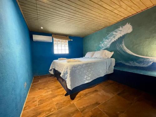 a blue room with a bed with a painting on the wall at Johnnys Place Hotel in Monterrico