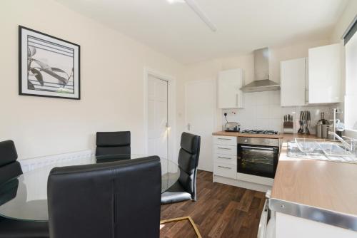 Alderton House - Spacious 3 Bed with Parking في نوتينغهام: مطبخ مع دواليب بيضاء وطاولة وكراسي