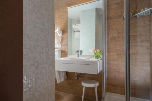 a bathroom with a sink and a mirror and a stool at Hotel Re Enzo in Bologna