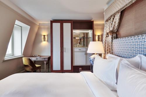a bedroom with a bed and a desk and a kitchen at De L’Europe Amsterdam – The Leading Hotels of the World in Amsterdam
