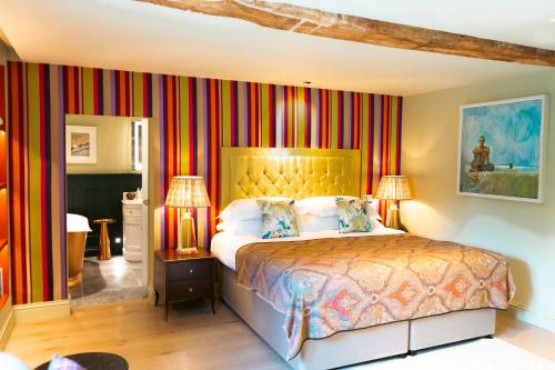 a bedroom with a king sized bed with striped walls at Bishopstrow Hotel and Spa - Small Luxury Hotels of the World in Warminster