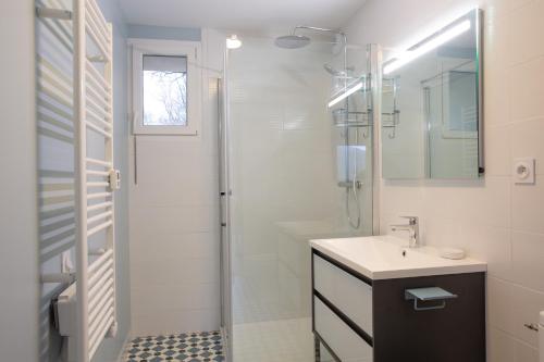 a white bathroom with a sink and a shower at Gîte de la Moulinquié in Saint-Cirgue