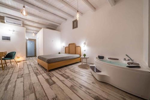 a bedroom with a tub and a bed and a bed and a table at Corte Janca in Montesano Salentino