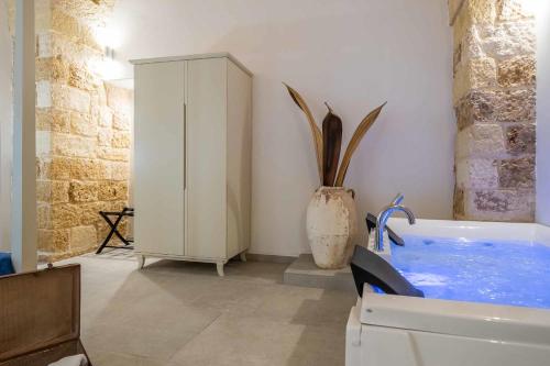 a bathroom with a tub and a vase with a plant at Corte Janca in Montesano Salentino
