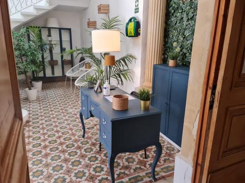 uma mesa azul com uma lâmpada sobre ela num corredor com plantas em Hostel On em Sliema