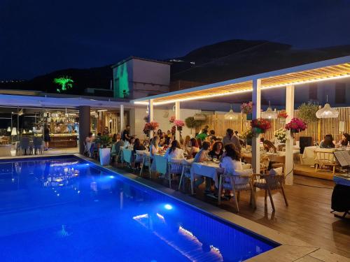 a group of people sitting around a pool at night at Regina City Hotel & SPA in Vlorë