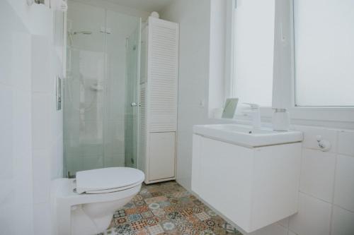 a white bathroom with a toilet and a sink at Domek przy winnicy 