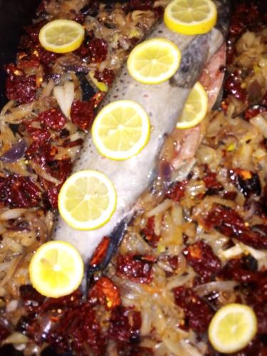 a close up of a fish with lemon slices on it at Guest House Stevovski in Ohrid