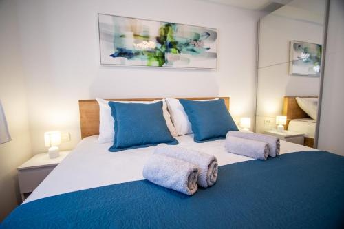 1 dormitorio con 1 cama grande con almohadas azules en Azzurro apartment - with rooftop jacuzzi en Zadar