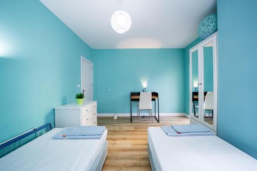 two beds in a room with blue walls and a desk at Colibri Central Apartment in Varna City