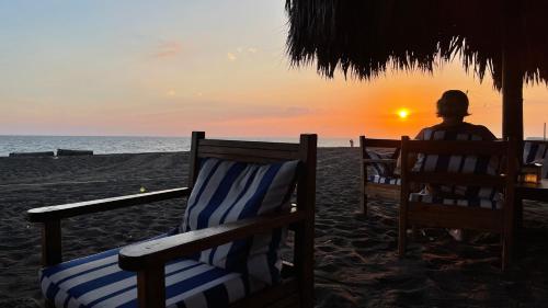 a person sitting on the beach watching the sunset at Johnnys Place Hotel in Monterrico
