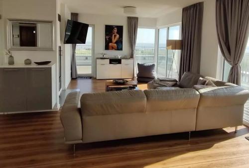 a living room with a large couch and a kitchen at Moin Mehrblick in Schillig