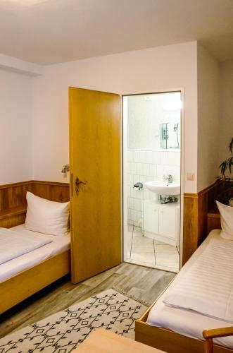 a room with two beds and a bathroom with a shower at Pension Bergstube in Bad Langensalza