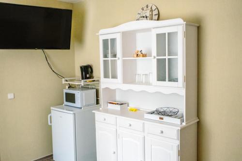 a white cabinet with a microwave and a tv at Pension Bergstube in Bad Langensalza