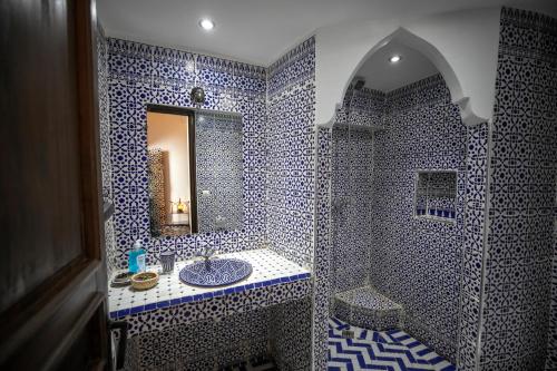 baño azul y blanco con lavabo y espejo en Dar Hafsa en Fez