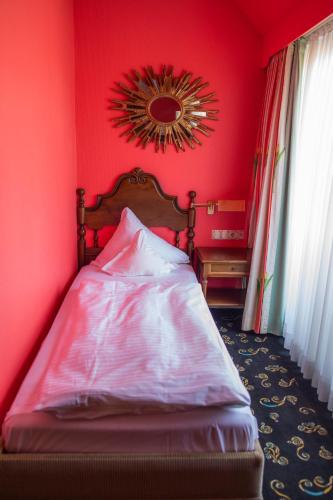 a bedroom with red walls and a bed with a mirror at Landhaus Hotel Neuss in Neuss