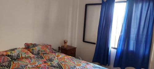 a bedroom with a bed with blue curtains and a window at Apart La Mochita II in San Fernando del Valle de Catamarca