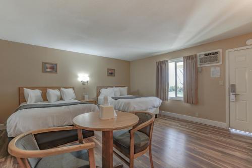 a hotel room with two beds and a table at Shasta Pines Motel & Suites in Burney