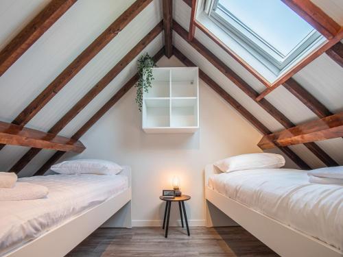 2 camas en un ático con vigas de madera en Gezellig vakantiehuis in Wolphaartsdijk bij het Veerse Meer, en Wolphaartsdijk