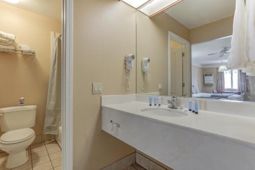 a bathroom with a sink and a toilet and a mirror at Shasta Pines Motel & Suites in Burney