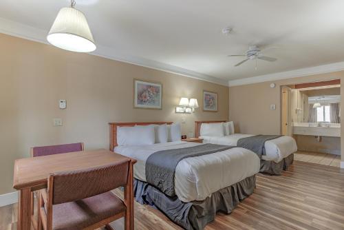 Burney的住宿－Shasta Pines Motel & Suites，酒店客房设有两张床和一张桌子。