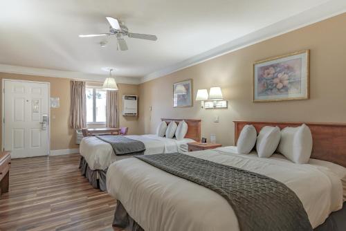 a hotel room with two beds and a ceiling fan at Shasta Pines Motel & Suites in Burney