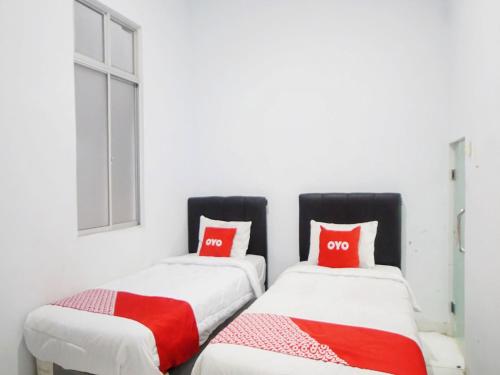 two beds in a room with red pillows at SUPER OYO 91627 Wika Wiki Homestay in Medan