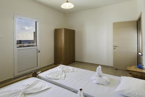 Un dormitorio con dos camas blancas y una ventana. en Georgias Apartments, en Charaki