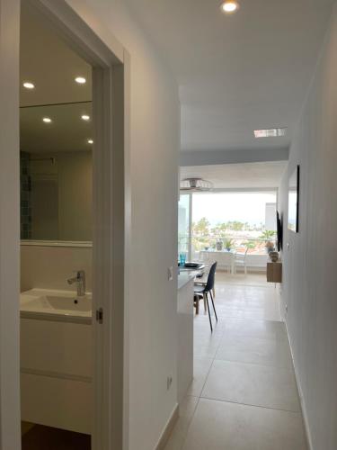a bathroom with a sink and a kitchen with a table at Apartamento Tamaran Sky in Playa del Ingles