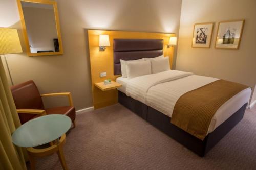 ブレントフォードにあるホリデイ イン ロンドン ブレントフォード ロックのベッドとテーブルが備わる小さなホテルルームです。