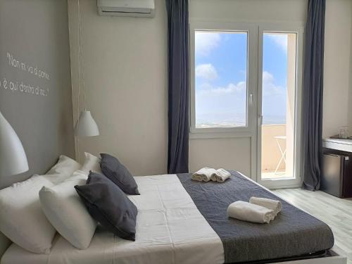 1 dormitorio con 1 cama grande con almohadas y ventana en Tuffudesu Experience, en Osilo