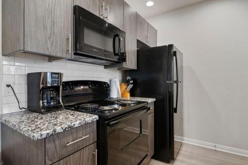 a kitchen with a stove and a black refrigerator at Downtown Luxury Apartment with King Bed in Waco