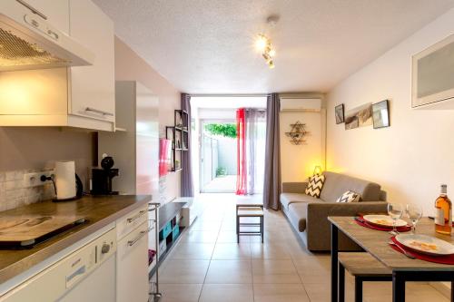 cocina y sala de estar con sofá y mesa en Beau studio avec grande terrasse, en La Grande-Motte