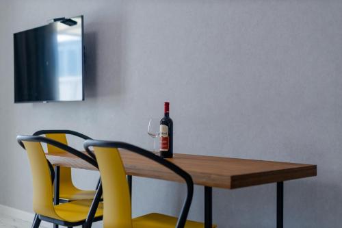a bottle of wine sitting on a wooden table with two chairs at The SPOT apartments - Orbi Beach Tower in Batumi