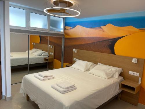 a bedroom with two beds and a painting on the wall at Apartamento Tamaran Sky in Playa del Ingles