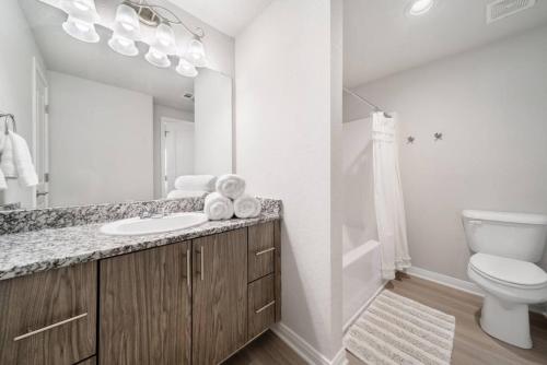 a white bathroom with a sink and a toilet at Trendy Downtown Waco Apartment With Great View in Waco
