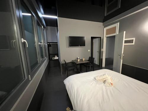 um quarto com uma cama branca e uma mesa com cadeiras em Logements des choraux em Tournai