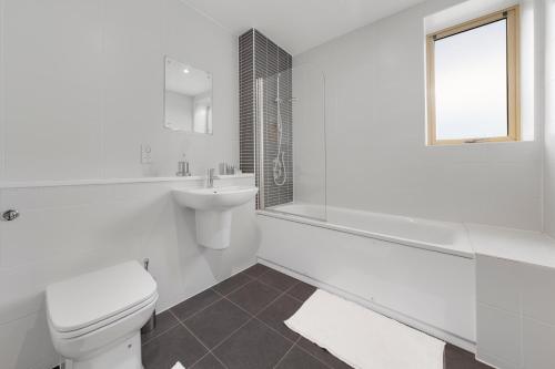 a white bathroom with a toilet and a sink at Flourish Apartments - Mulberry House - Tottenham in London