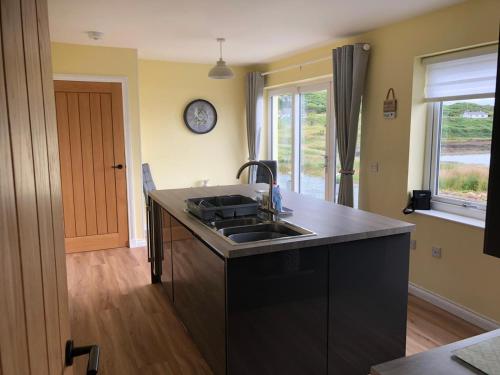 a kitchen with a sink and a clock on the wall at Loch Caroy Bay Cottage in Ose