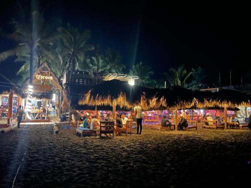 a group of people sitting on a beach at night at Johnnys Place Hotel in Monterrico