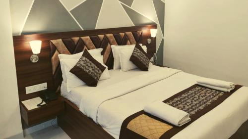 a bedroom with a large bed with white sheets and pillows at Rajdhani Resort Lonavala in Lonavala