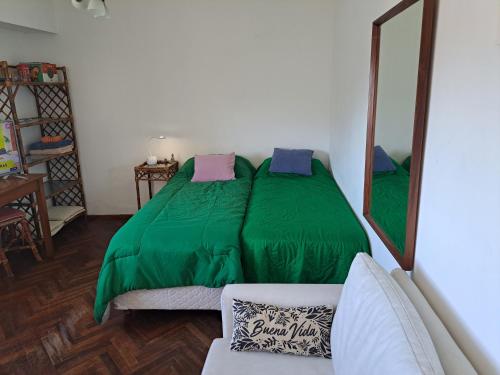 a bedroom with a green bed and a mirror at Dpto El Cairo, tu lugar en Rosario in Rosario